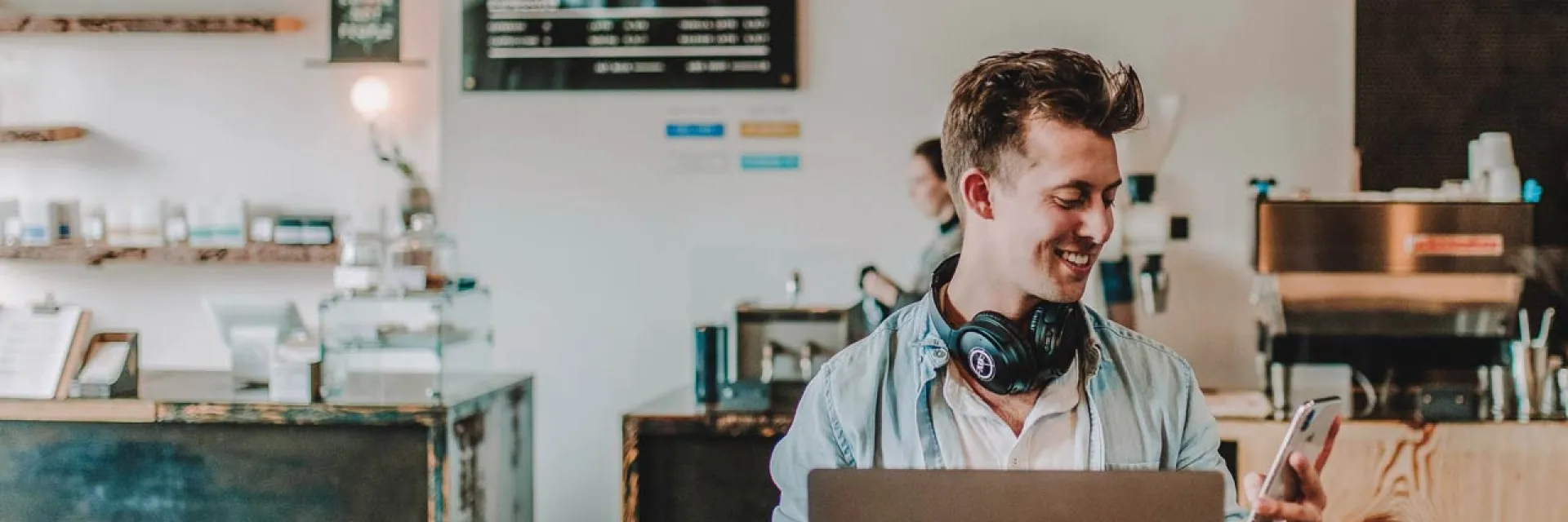 Hombre mirando el móvil mientras está trabajando en una cafetería