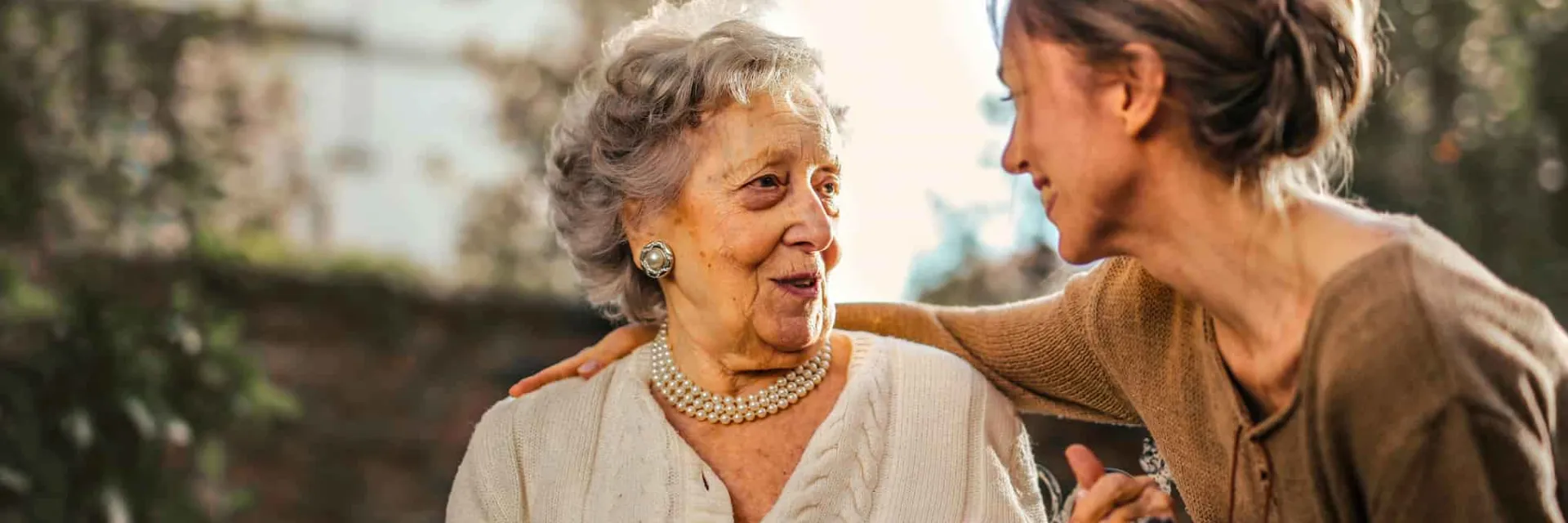 Una cuidadora de personas mayores sonríe, hablando con una paciente.