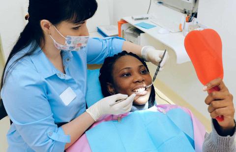 Dentista enseña a su paciente la endodoncia que ha hecho en sus dientes.