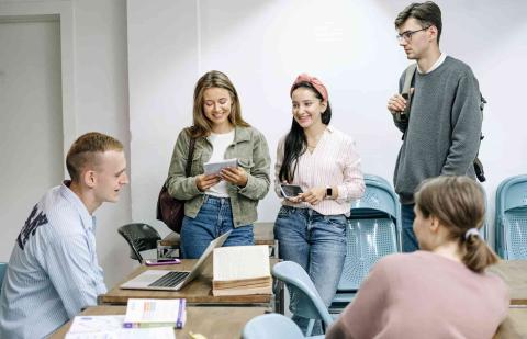 Estudiantes sonríen en un aula con un portátil