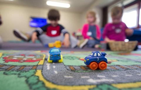 Niños de educación infantil jugando en el suelo con coches de juguetes