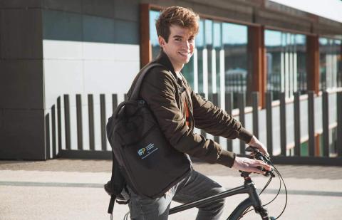 Chico joven en bici sonriendo mientras va a clase