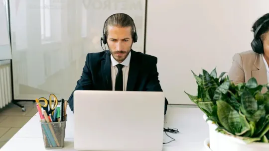 Chico hablando por teléfono con ordenador 