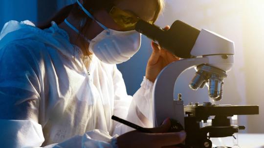 Hombre trabajando con un microscopio en un laboratorio químico
