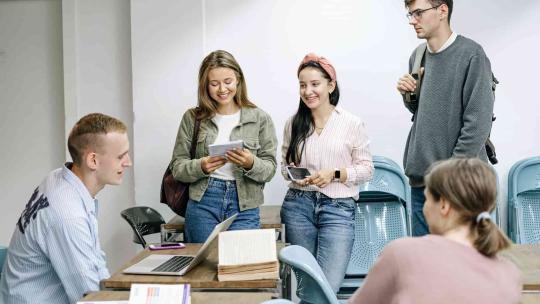 Estudiantes sonríen en un aula con un portátil