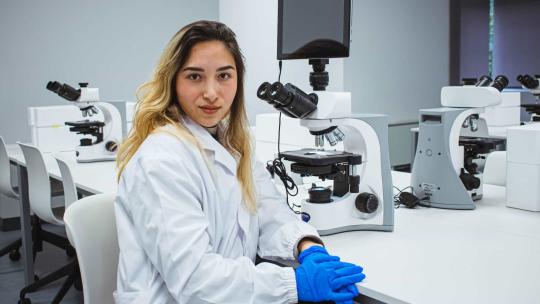 Técnica de laboratorio realiza investigación médica con un microscopio.