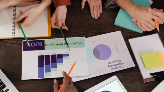 Mesa de trabajo donde un equipo de marketing analiza las métricas de una campaña publicitaria. 