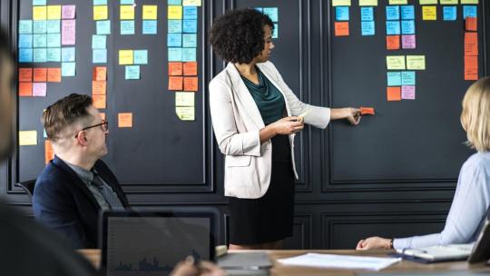 Grupo de personas en una reunión de trabajo, explicando con posit los puntos a tratar