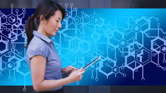 Una mujer con un portátil delante de un fondo representativo de blockchain.