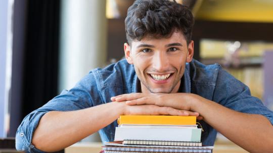 Estudiante de grado superior con libros en la biblioteca.