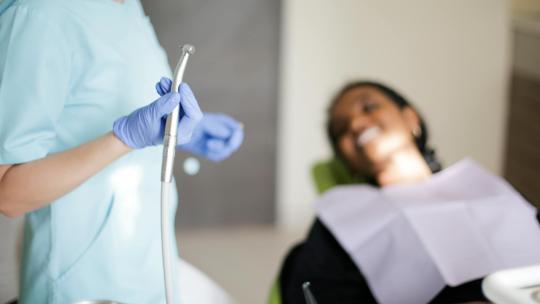 Dentista realiza un curetaje dental en una paciente.