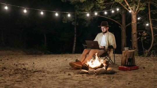 Un hombre estudia de noche en un camping.