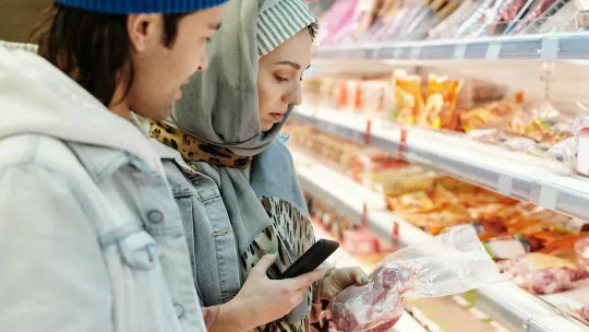 Dos jovenes miran la etiqueta nutricional de un producto en el supermercado.