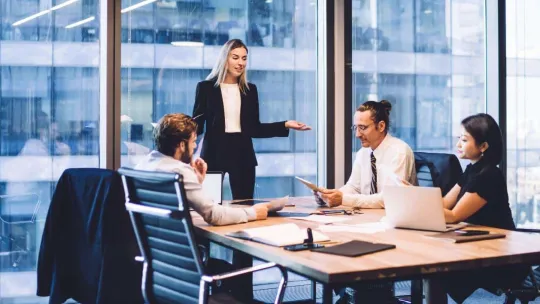 Equipo de Administración y Finanzas discute proyecto en una oficina. 