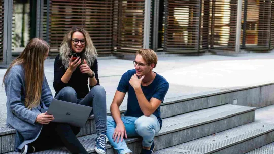 tres personas sentadas en las escaleras hablando entre si