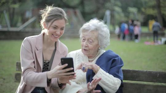 Mujer enseñando tecnologia a una señora mayor