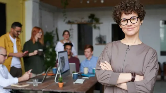 foto de mujer joven con gafas y brazos cruzados en una oficina