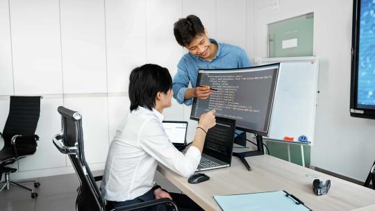Dos hombres jóvenes aprenden a programar y practican sus habilidades de lógica juntos.