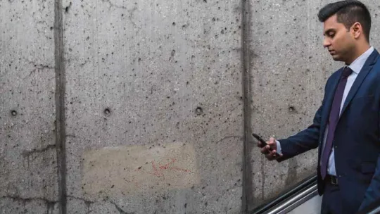 Hombre de negocios, que trabaja en relaciones públicas, bajando escaleras mecánicas y mirando su móvil.