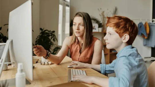 Niño y su madre estudiando juntos en un ordenador