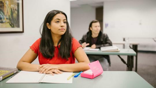 Chica joven atendiendo en clase con un cuaderno en la mesa