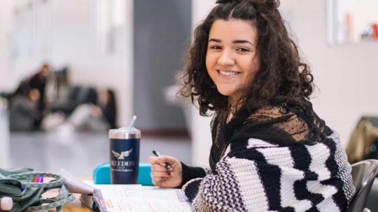 Estudiante joven sonriendo mientras escribe en su cuaderno