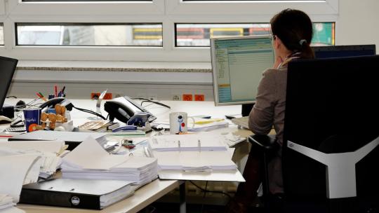 Trabajadora en su puesto de trabajo con muchos documentos.