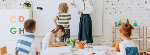 Profesora en pizarra con niños 