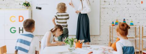 Profesora en pizarra con niños