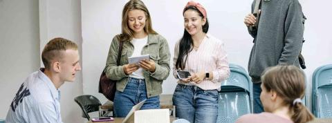 Estudiantes sonríen en un aula con un portátil