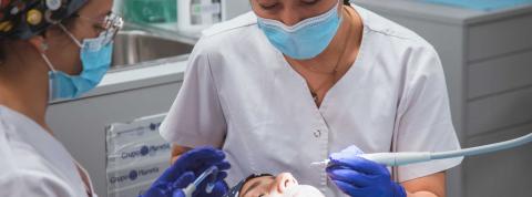 Higienista Bucodental y odontóloga realizan un tratamiento en una clínica dental.