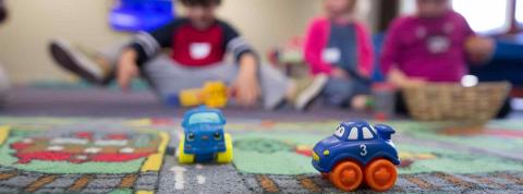 Niños de educación infantil jugando en el suelo con coches de juguetes