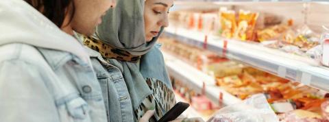Dos jovenes miran la etiqueta nutricional de un producto en el supermercado.