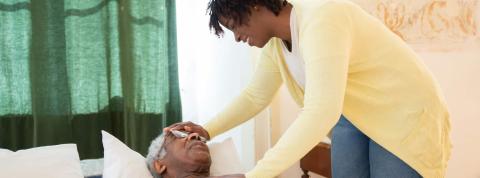 Mujer cuida de un paciente anciano encamado.