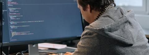 Hombre programando con una pantalla de ordenador