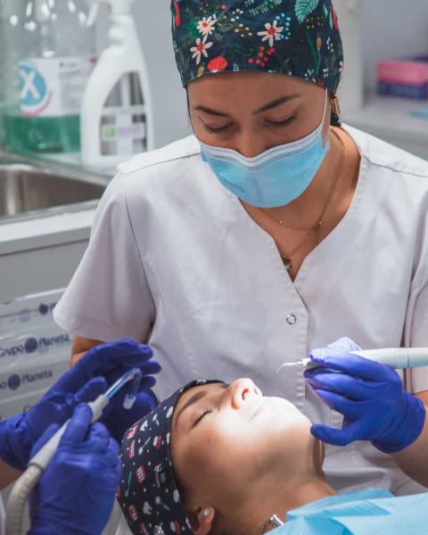 Higienista Bucodental y odontóloga realizan un tratamiento en una clínica dental.