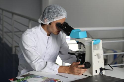 Técnico en Laboratorio de Diagnóstico Clínico con microscopio y bata.